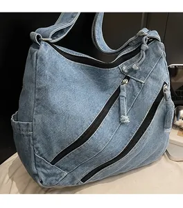 Close-up of vintage blue denim tote bag featuring triple diagonal zippers and frayed edges