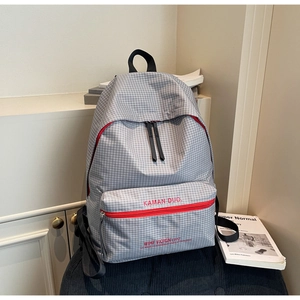 Detail of grey plaid backpack featuring red zipper accents and KAMAN DUO logo branding