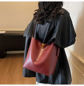 Detail of burgundy waxed leather bucket bag with gold twist lock and fashion bag logo