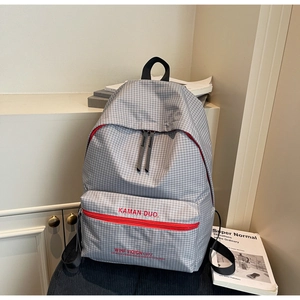 Detail of grey plaid canvas backpack featuring a red zipper and minimalist kaman duo logo