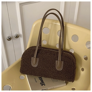 Détail de la texture moumoute du sac bowling marron avec anses en cuir sur chaise