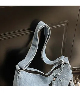 Detail view of adjustable denim strap with frayed edges and silver hardware