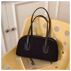 Détail du sac à main noir en peluche bouclée avec anses en cuir sur une chaise design