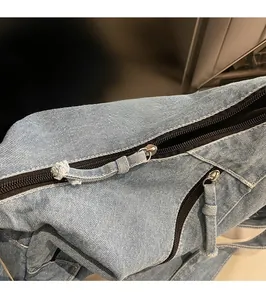 Detailed close-up of smooth metal zipper and denim patchwork on this shoulder bag