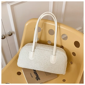 Gros plan d'un sac bowling en polaire blanche avec poignées en cuir sur une chaise