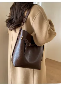 Détail du sac seau en similicuir marron foncé avec boucle dorée sur le côté du sac