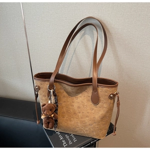 Detail of vintage brown tote bag with embossed puppy patterns and plush bear charm