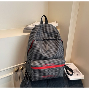 Close-up of black and white plaid backpack with red zipper detail and brand logo