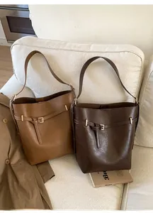 Gros plan de sacs seaux vintage en marron clair et foncé avec boucle dorée élégante