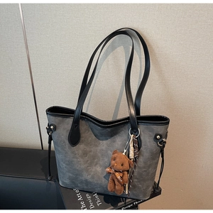 Detail view of grey tote bag with animal pattern texture and cute teddy bear charm