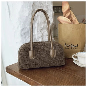 Gros plan d'un sac à main marron en peluche avec anses en cuir dans un décor de café
