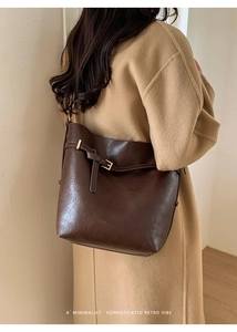 Sac seau chic marron foncé à texture litchi porté avec un manteau d'hiver beige élégant