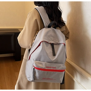 Detailed view of gray checkered backpack with red zipper accents and reinforced straps
