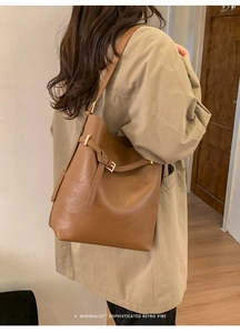 Détail d'un sac cabas en cuir marron avec boucle en métal doré et texture vintage