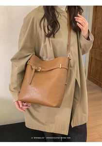 Détail du sac seau caramel avec lanière en cuir, boucle dorée et texture plissée