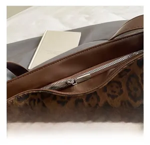Detail of silver metal zipper closure on leopard print shoulder bag with brown trim