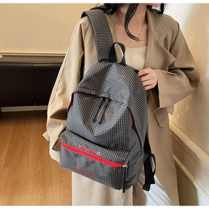 Detailed view of large capacity black and white checkered canvas backpack with red zippers