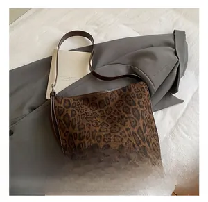 Close-up of leopard print tote bag texture with brown leather strap on blazer