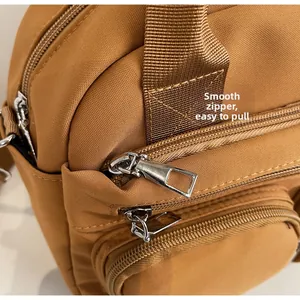 Detail of smooth metal zippers and layered pockets on brown corduroy crossbody bag
