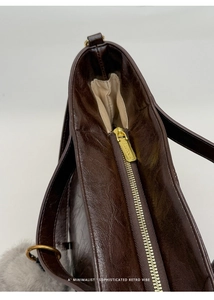 Detailed close-up of dark brown vintage oil wax leather tote bag with gold metal zipper