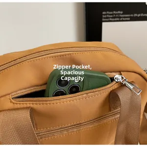 Detail of front zipper pocket on ginger nylon crossbody bag showing smartphone storage