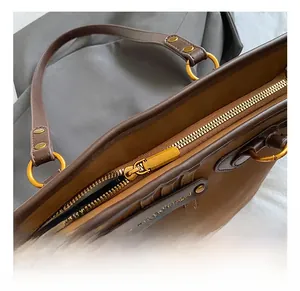 Detail of golden metal zipper and brand leather tag on a brown tote bag