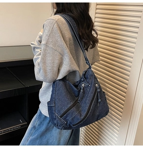 Detail of blue denim hobo bag showing retro wash effect and functional zipper pockets