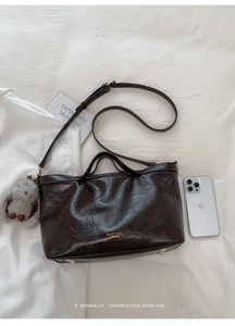 Detail of vintage dark brown faux oil wax leather tote bag with golden logo and plush rabbit charm