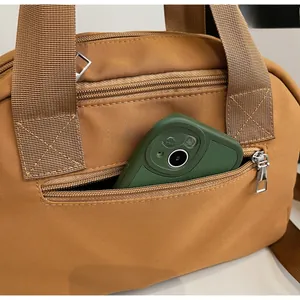 Front zipper pocket detail of the brown crossbody bag showing storage for a smartphone