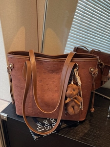 Brown tote bag with puppy embossing and a plush bear charm for a stylish casual look