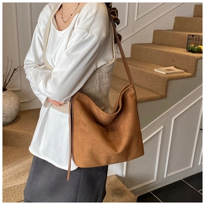 Close-up of brown suede hobo bag with sleek shoulder strap in a stylish indoor setting