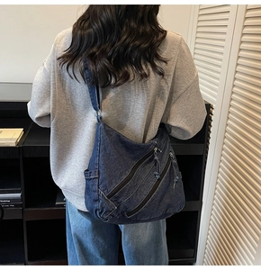 Détail d'un sac cabas en denim bleu avec plusieurs poches zippées sur un sac à bandoulière
