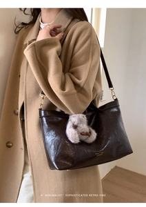 Close-up of vintage brown leather tote bag with gold logo and plush pendant detail