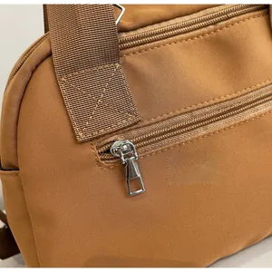 Detail of smooth metal zipper and durable nylon fabric on khaki crossbody bag