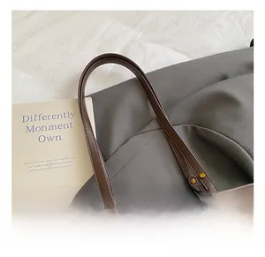 Detail of brown tote bag handle with vintage gold rings and fine stitching craftsmanship