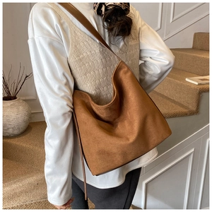 Detail of a large brown suede hobo bag with slim leather straps for daily commute