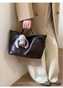 Detail of dark brown leather tote bag with plush rabbit charm and branded logo