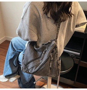 Détail d'un sac bandoulière rétro en denim noir délavé avec fermetures éclair pratiques