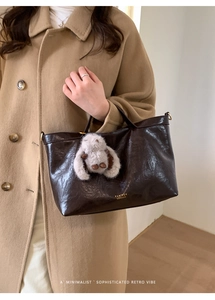 Detail of dark brown vintage oil wax tote bag with gold lettering and plush rabbit charm