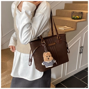 Détail d'un cabas en cuir mat marron foncé orné d'un joli charm d'ourson en peluche