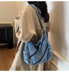 Vue détaillée d'un grand sac hobo en jean vintage avec plusieurs zips porté par un mannequin