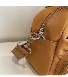 Close-up of durable metal hook and zipper detail on brown nylon shoulder bag