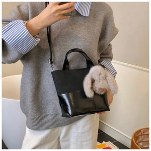 Detailed view of canvas and leather bucket bag with a cute plush bunny charm