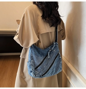 Detailed close-up of blue washed denim crossbody bag with metallic zipper accents