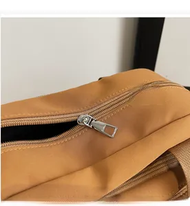 Detail of smooth silver zipper hardware and canvas texture on brown shoulder bag