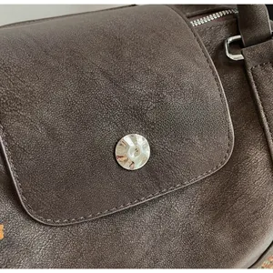 Detail of dark brown vintage faux leather texture and metallic buckle on tote bag