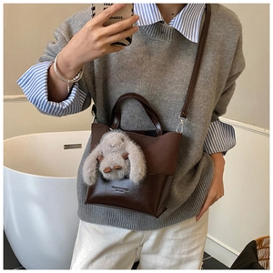 Close-up of vintage brown leather bucket bag with a cute plush bunny charm detail