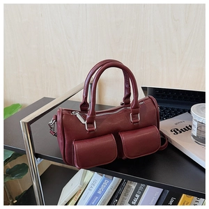 Detailed macro view of the burgundy Boston bag with dual magnetic flap front pockets