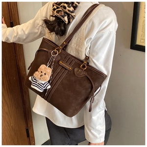 Détail du sac cabas marron foncé avec logo en métal et pendentif ours mignon