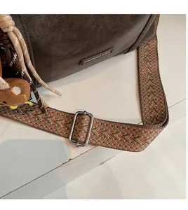 Detail of adjustable bohemian woven shoulder strap with metallic buckle on a brown leather bag